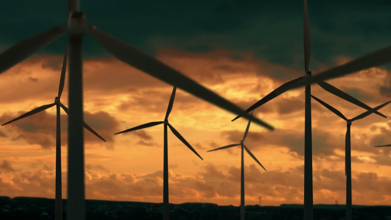 Wind turbines spread across a hillside at sunset