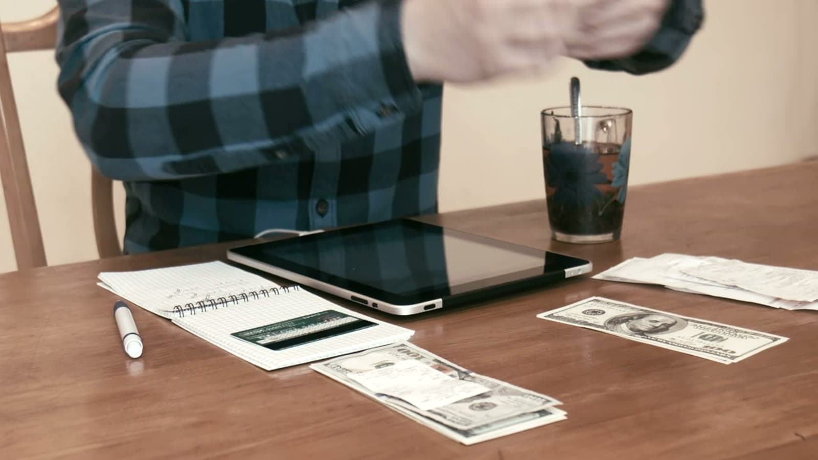 Hands sorting cash into separate budget envelopes on a desk