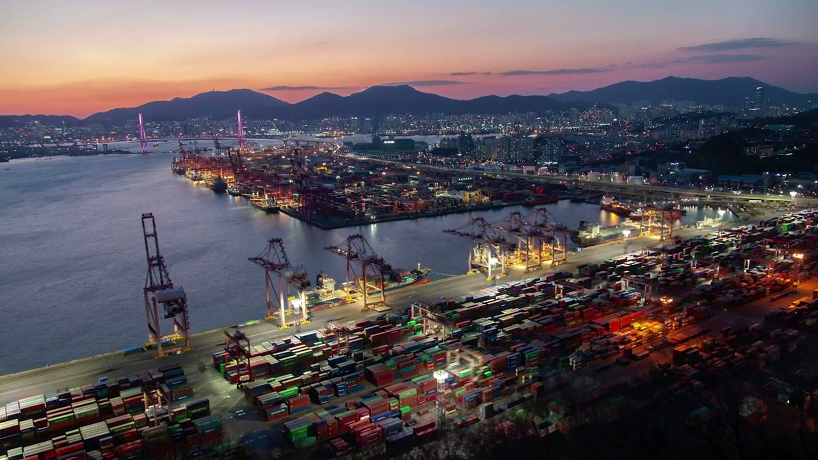 Aerial view of a container port with rows of stacked shipping containers and gantry cranes
